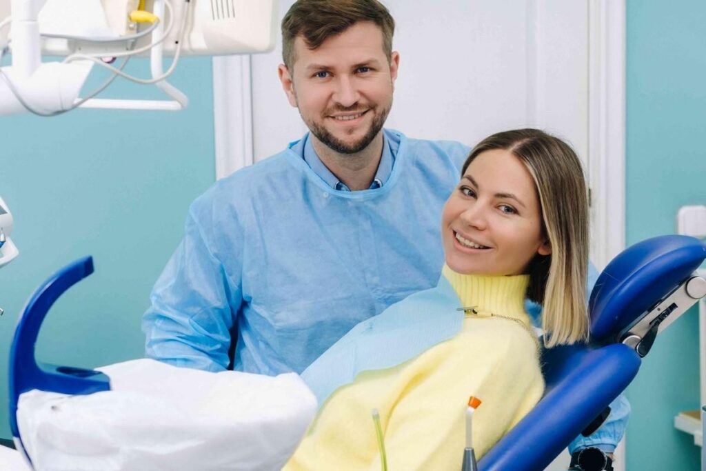 Dentist standing beside a smiling patient seated in a dental chair