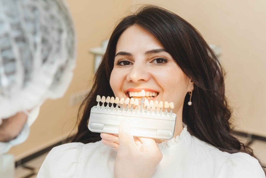 Woman comparing veneer shades with a dentist during a cosmetic dental consultation